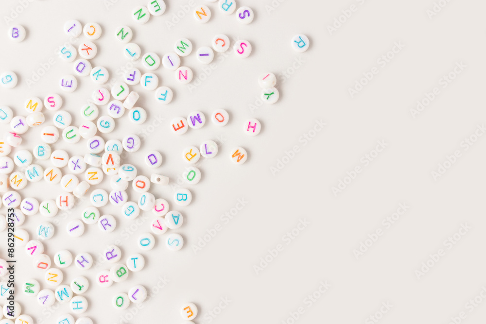 Beads with letters scattered on a beige background. Place for your design.
