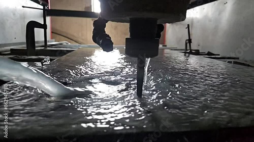 Diamond cutting scene with Computer Numerical Control (CNC) machine. Water jets fly in different directions, slow motion.