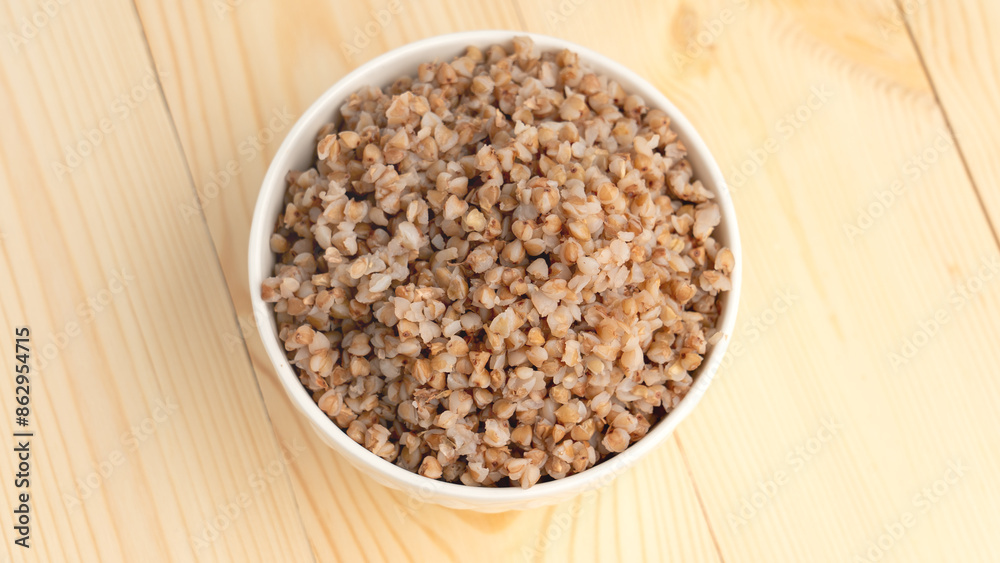 buckwheat porridge in a round white plate on a wooden table. Close-up view from above buckwheat porridge in a round white plate on a wooden table. Close-up view from above