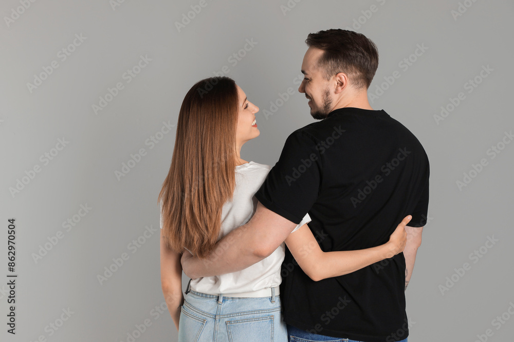 Cute couple hugging on grey background, back view. Space for text Cute couple hugging on grey background, back view. Space for text