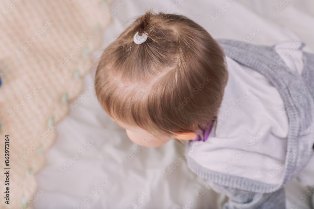 Baby girl playing on a bed and looking down Baby girl playing on a bed and looking down