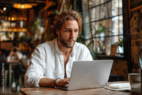 A man works on a laptop in a cafe. Remote work, study and freelancing concept.
