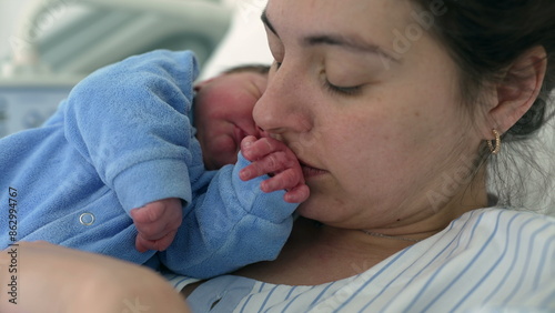 Mother kissing newborn baby's hand during the initial hours of life of a new human being. Mom and infant heartwarming moment, maternal care and motherhood concept