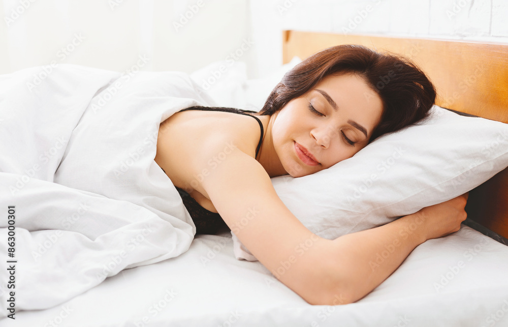 A woman is peacefully asleep in a bed with crisp white sheets covering her. The room is softly lit, creating a cozy and restful atmosphere. A woman is peacefully asleep in a bed with crisp white sheets covering her. The room is softly lit, creating a cozy and restful atmosphere.