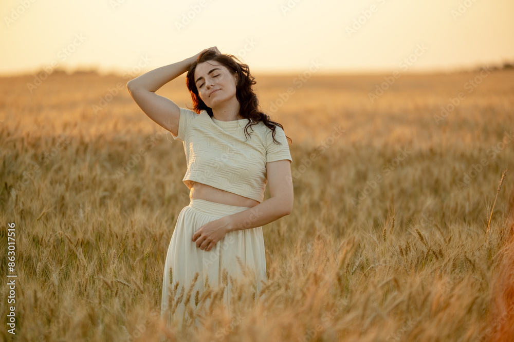 A young brunette walks in wheat fields at sunset in summer. Growing organic wheat and barley. A young brunette walks in wheat fields at sunset in summer. Growing organic wheat and barley.