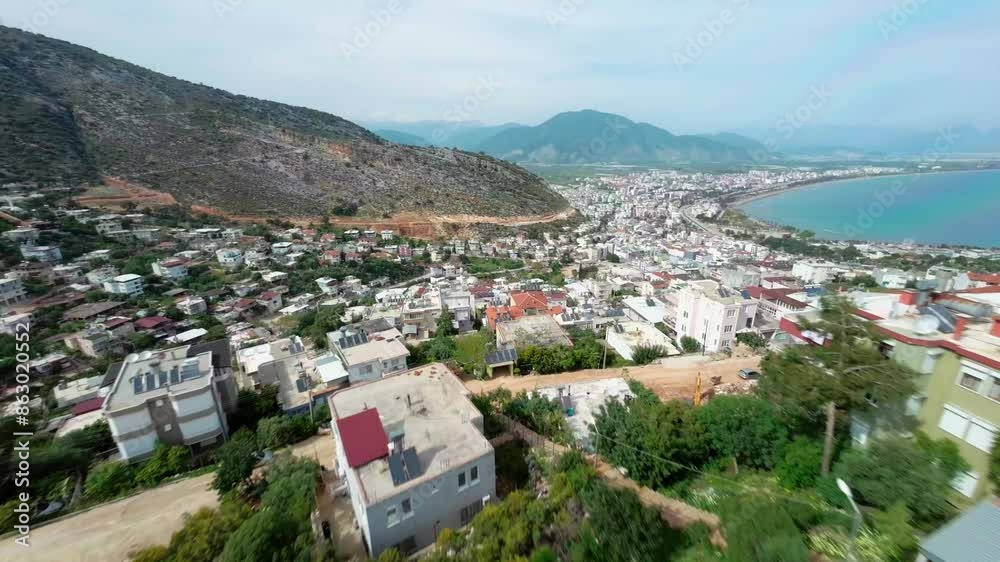 aerial view of a coastal town nestled between the sea and mountains. The town is characterized by a mix of residential buildings and green spaces, with a clear view of coastline and blue waters of sea aerial view of a coastal town nestled between the sea and mountains. The town is characterized by a mix of residential buildings and green spaces, with a clear view of coastline and blue waters of sea