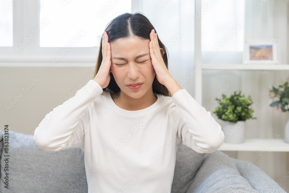Dizzy asian young woman, girl headache or migraine pain suffering from vertigo while sitting on couch in living room at home, holding head with hand, health problem of brain or inner ear not balance. Dizzy asian young woman, girl headache or migraine pain suffering from vertigo while sitting on couch in living room at home, holding head with hand, health problem of brain or inner ear not balance.