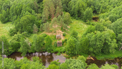 Top view of green forest with trees and river Merkys, railway bridge remains, Senoji Varena, Lithuania