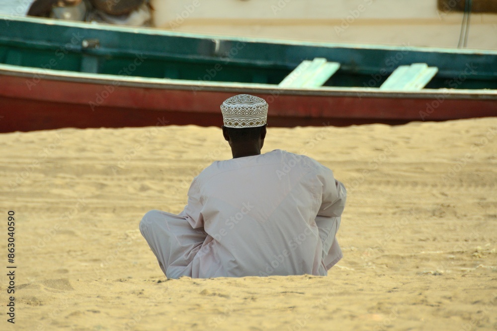 Hombre sentado en la arena en Qurayyat, Sultanato de Omán