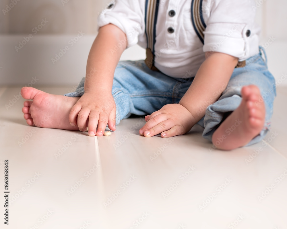 Small child sitting barefoot, grabbing for a piece of cereal Small child sitting barefoot, grabbing for a piece of cereal