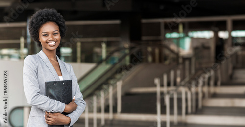 Schilderij op canvas Portrait of young female African American job seeker keeping a folder with CV in her hands standing against office building