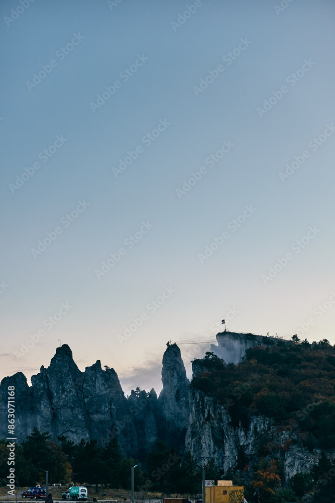 Obraz premium Scenic Mountain View from Road in Front of FlagTopped Building Travel Destination Inspiration with Business Potential