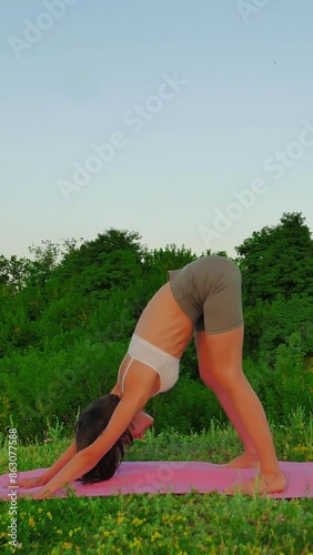 young white woman with dark hair and a short haircut in a white top and leggings does yoga in nature at sunset