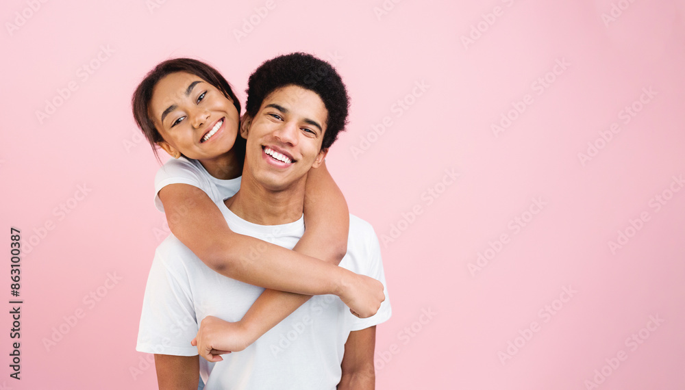 Fototapeta premium Loving girl embracing guy, posing to camera on pink studio background