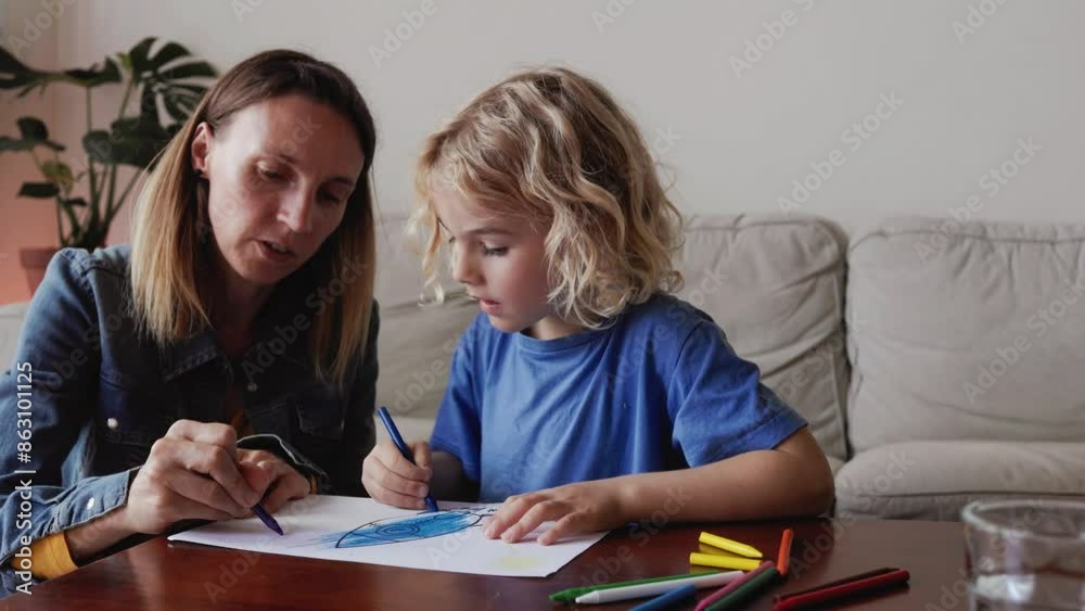Mother and son child drawing together having fun inside home living room Mother and son child drawing together having fun inside home living room