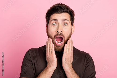 Portrait of crazy horrified man with bristle stylish hairdo wear brown shirt arms on cheeks scream isolated on pink color background