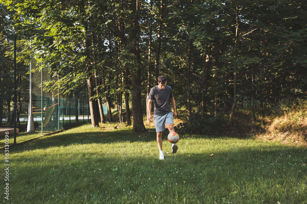 Black-haired athlete plays a friendly football match on the lawn. Amateur sport. Man playing with a ball. Dribbling practice. Sport lifestyle Black-haired athlete plays a friendly football match on the lawn. Amateur sport. Man playing with a ball. Dribbling practice. Sport lifestyle