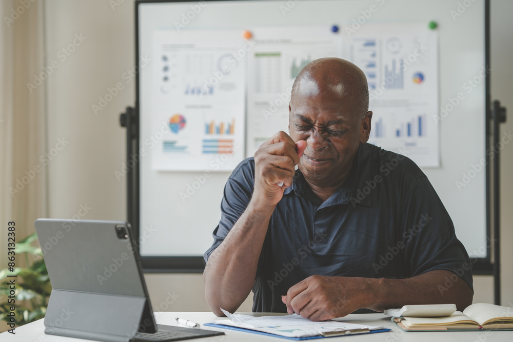 Businessman analyzing data on a tablet at desk with charts in the background, office setting, thoughtful expression while working. Businessman analyzing data on a tablet at desk with charts in the background, office setting, thoughtful expression while working.