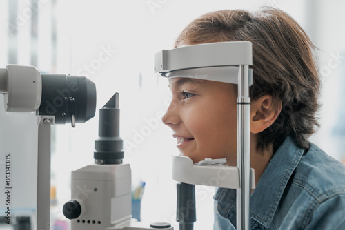 Side view shot of boy checking vision with tonometer at eye clinic photo