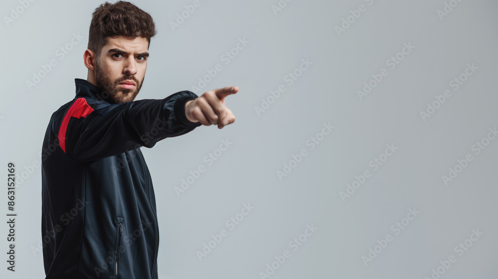 Serious man in sports jacket pointing forward against neutral background. He has focused expression and dark hair Serious man in sports jacket pointing forward against neutral background. He has focused expression and dark hair