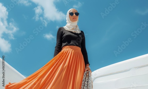 Woman in Orange Pleated Skirt and White Hijab Posing Against a Blue Sky