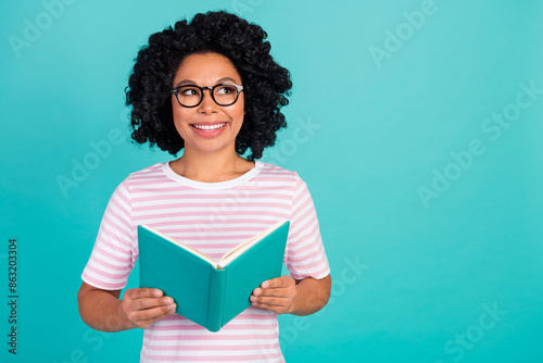 Photo portrait of lovely young lady look empty space read book dressed stylish striped garment isolated on aquamarine color background
