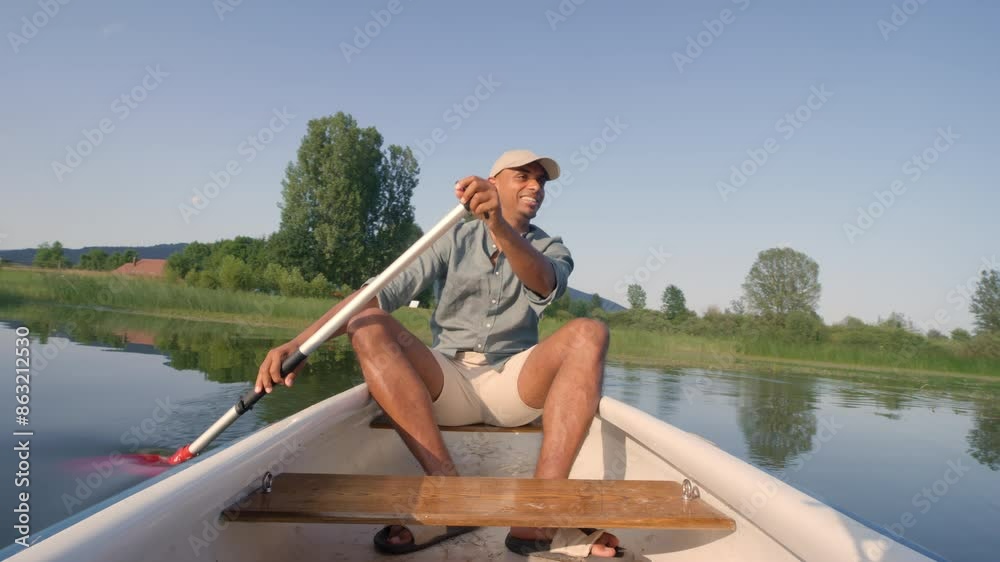 Smiling young man enjoying holiday travel activity on the lake, paddling a canoe and relaxing surrounded by peaceful summer nature, front view. Smiling young man enjoying holiday travel activity on the lake, paddling a canoe and relaxing surrounded by peaceful summer nature, front view.