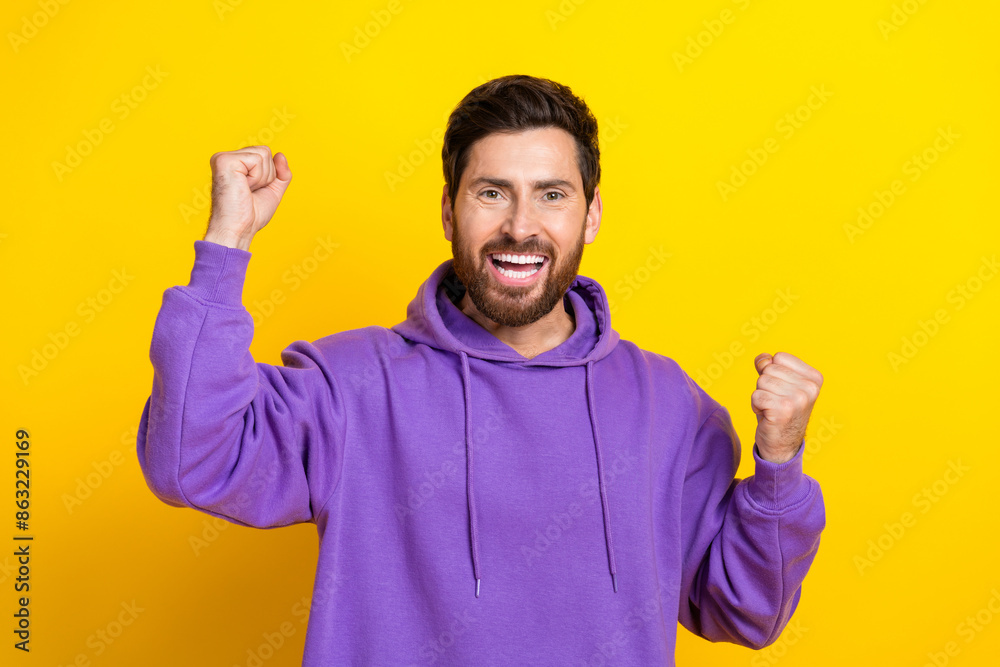 Photo portrait of handsome young guy winning raise fists wear trendy violet outfit isolated on yellow color background