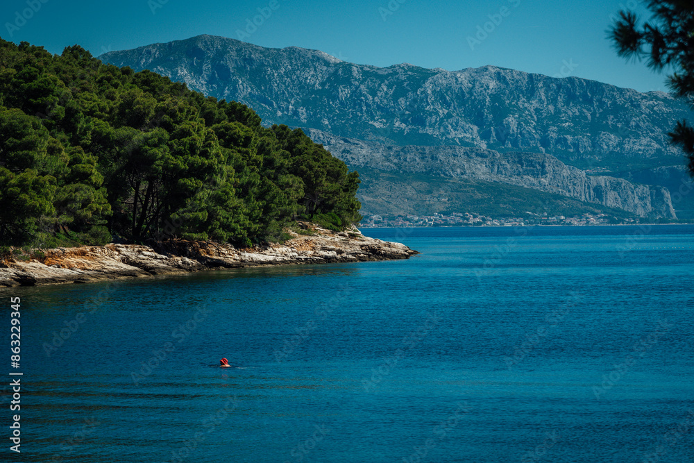Beautiful view of the sea with someone swimming in it and mountains from the island Brac in Croatia while traveling in Europe. Beautiful view of the sea with someone swimming in it and mountains from the island Brac in Croatia while traveling in Europe.