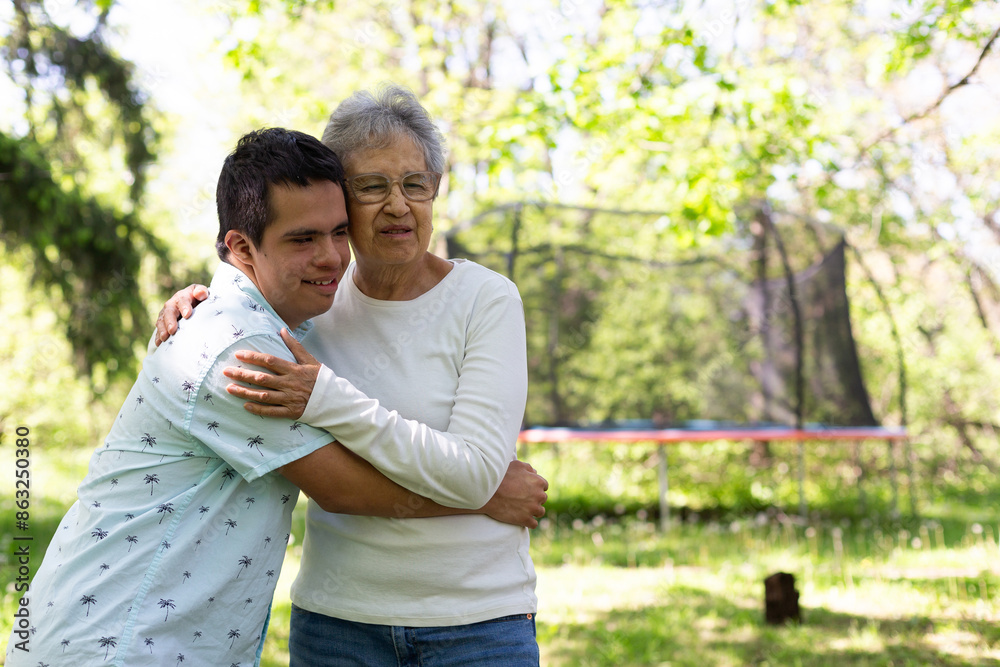 A man and an old woman embrace in a park. The man is wearing a blue shirt . The scene is peaceful and touching. A man and an old woman embrace in a park. The man is wearing a blue shirt . The scene is peaceful and touching.
