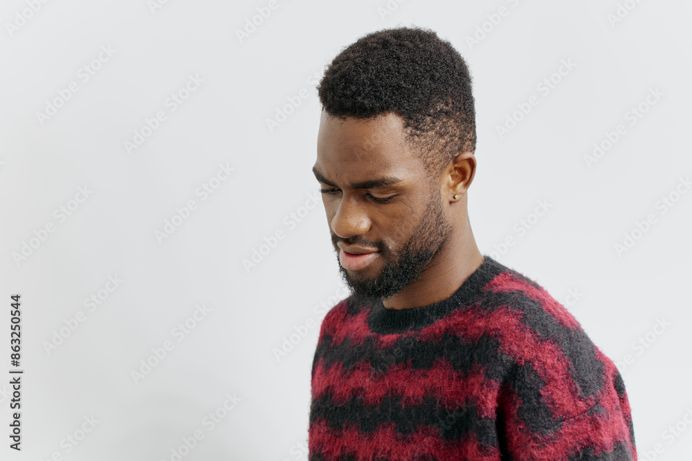 Obraz premium Confident young african american man in stylish red and black sweater posing against a neutral background