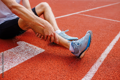 Athlete holding his leg injured after running at track and field stadium after jogging photo