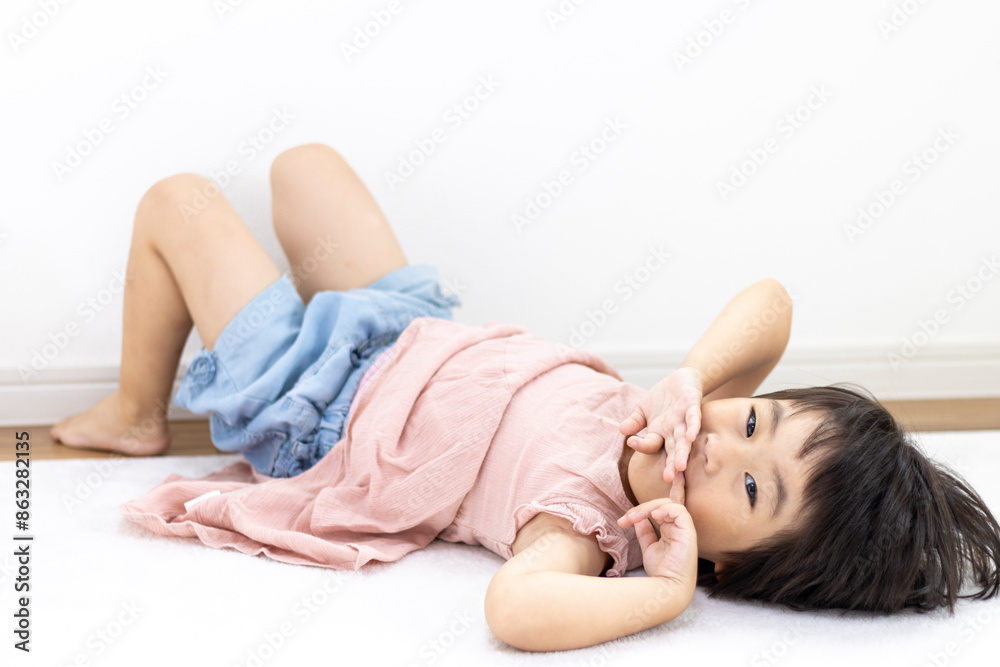 Obraz premium 絨毯に寝転がる笑顔の女の子（3歳、日本人、ショートヘア）