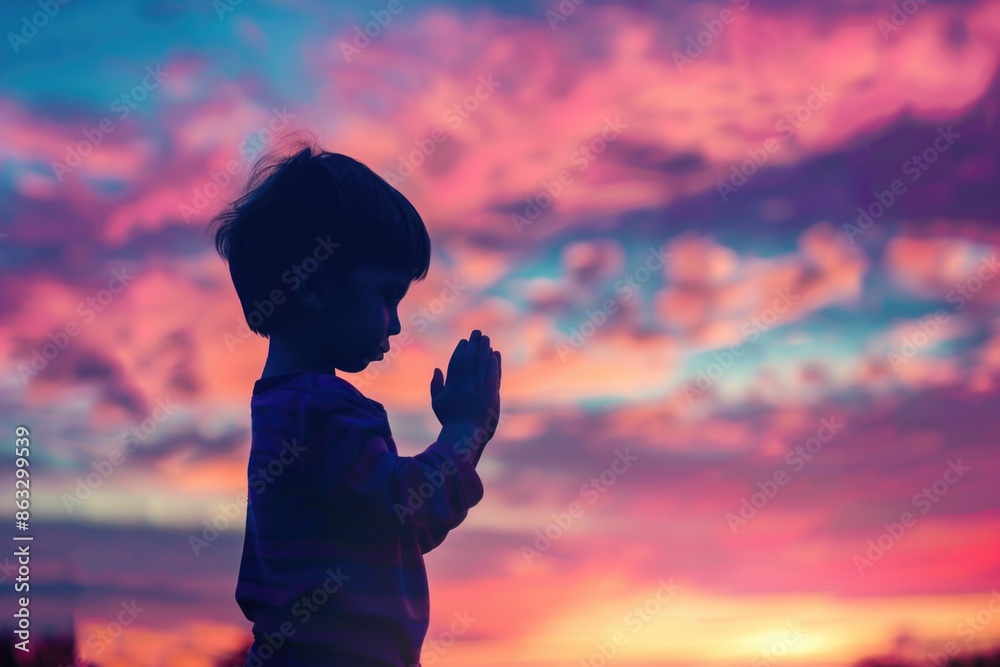 Fototapeta premium A young boy stands alone admiring the beautiful sunset
