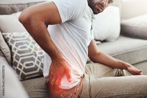 Back pain, hands and man on sofa with inflammation glow, joint or anatomy risk in his home. Red, backache and male person in a living room with muscle, burnout or spine, bone and emergency in house