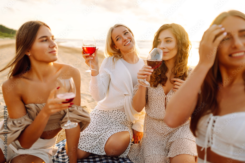 Group of young women having fun enjoying a beverage and relaxing on the beach at sunset. Hen party on the beach. Vacation, relax, holiday, picnic. Group of young women having fun enjoying a beverage and relaxing on the beach at sunset. Hen party on the beach. Vacation, relax, holiday, picnic.