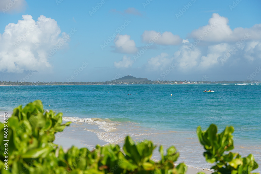 A blurry beach with an island, water, clouds, vegetation, azure sky A blurry beach with an island, water, clouds, vegetation, azure sky