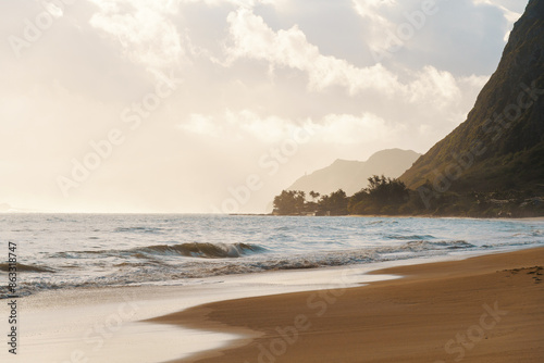 A beach with a mountain, waves crashing on the sand