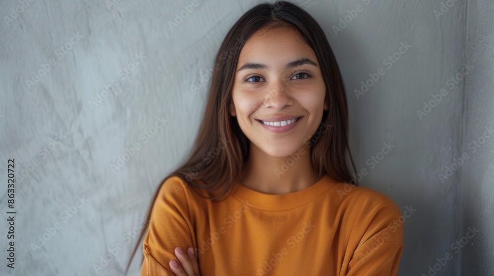 A portrait of a young, Hispanic woman with a pleasant smile and crossed arms. She is wearing a yellow shirt and standing against a grey wall. Generative AI A portrait of a young, Hispanic woman with a pleasant smile and crossed arms. She is wearing a yellow shirt and standing against a grey wall. Generative AI