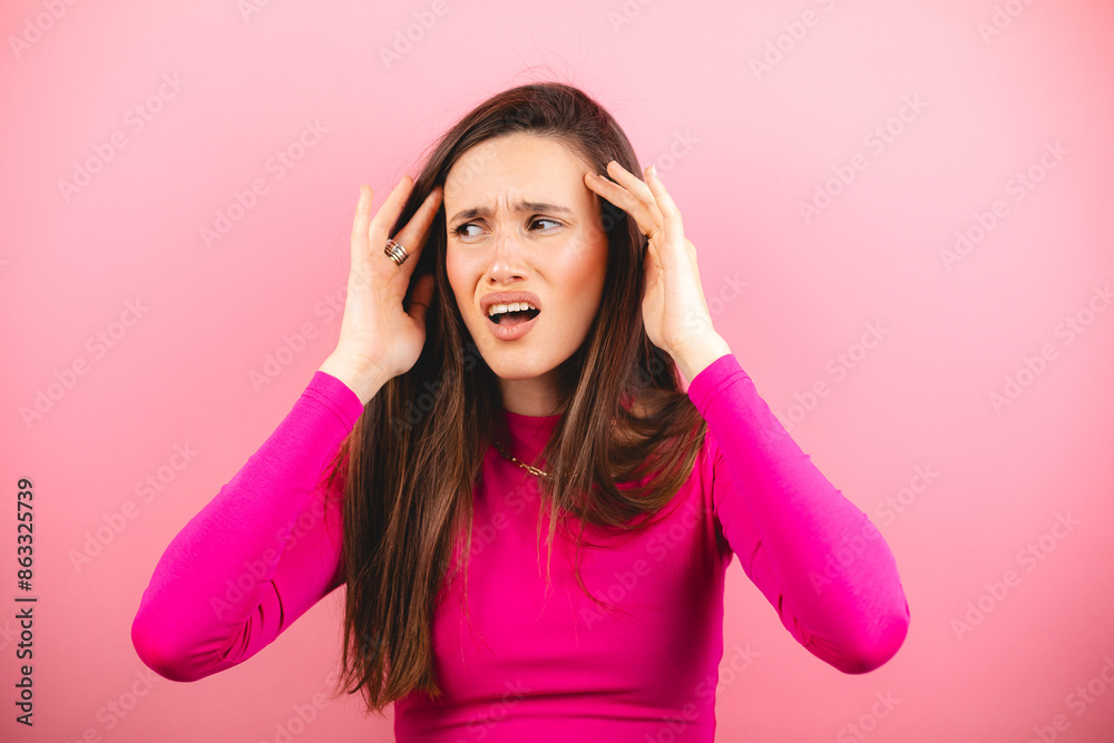 Closeup photo of young attractive annoyed angry woman wear pink long sleeves hands hold head nervous deadline isolated on pink color background. Girl feels troubled and concerned, headache or migraine Closeup photo of young attractive annoyed angry woman wear pink long sleeves hands hold head nervous deadline isolated on pink color background. Girl feels troubled and concerned, headache or migraine