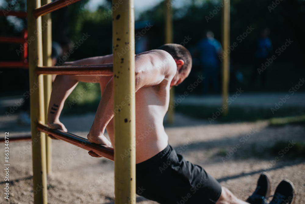 Obraz premium Athletic man executing a dip exercise on parallel bars in an outdoor gym setting, focusing on strength and fitness.