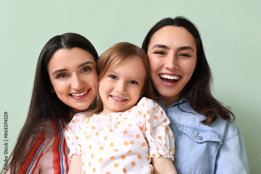 Young lesbian couple with adopted little girl on green background, closeup Young lesbian couple with adopted little girl on green background, closeup