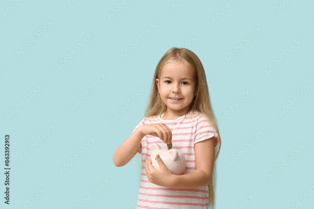 Cute little girl putting money into piggy bank on blue background Cute little girl putting money into piggy bank on blue background