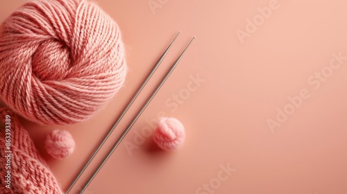 Knitting supplies with a ball of wool and straight needles isolated on a solid peach background photo