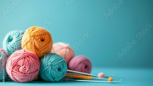 Knitting supplies with a ball of yarn and crochet hooks isolated on a solid aquamarine background