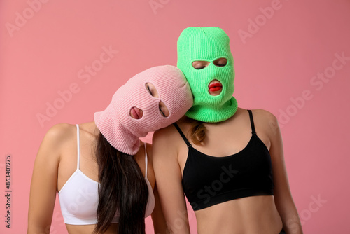 Beautiful young stylish women in balaclavas and sexy underwear on pink background