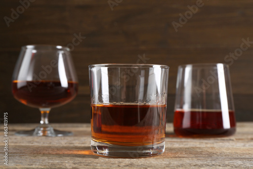 Different delicious liqueurs in glasses on wooden table