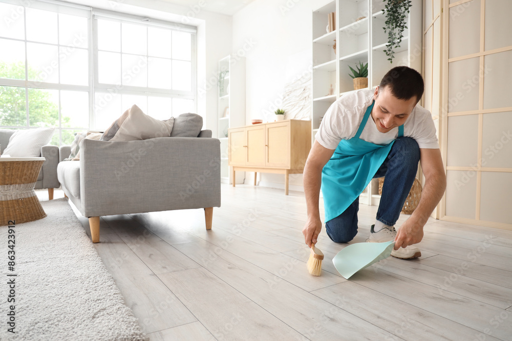 © Pixel-Shot - Male janitor sweeping floor in room