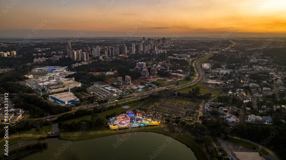 Fototapeta premium Curitiba in Paraná, Brazil. Aerial View. Wonderful sunset with views of buildings and Tanguá Park. Lake with reflection..