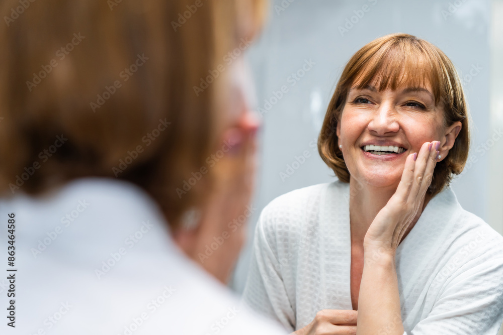 © Kawee - Caucasian senior woman looking at mirror then apply lotion on face. © Kawee - Caucasian senior woman looking at mirror then apply lotion on face.